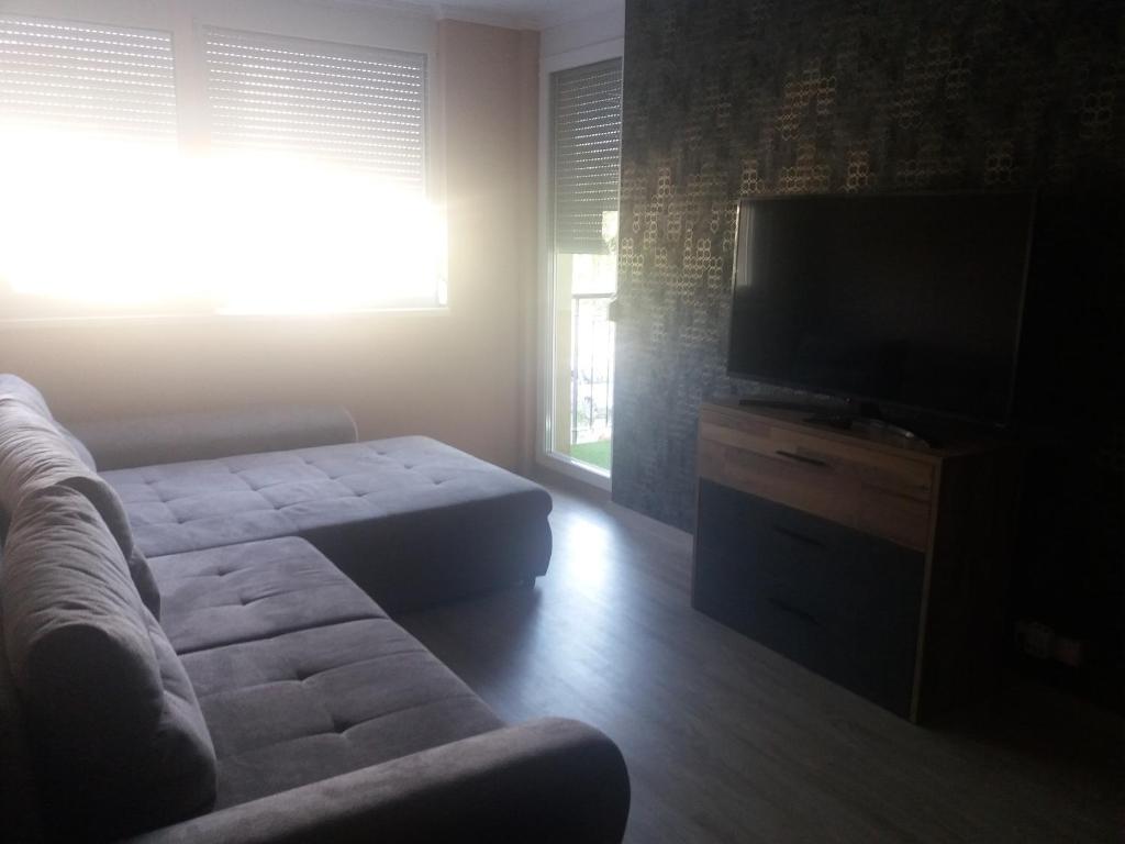 a living room with a couch and a flat screen tv at Silver Gellért Apartman in Siófok