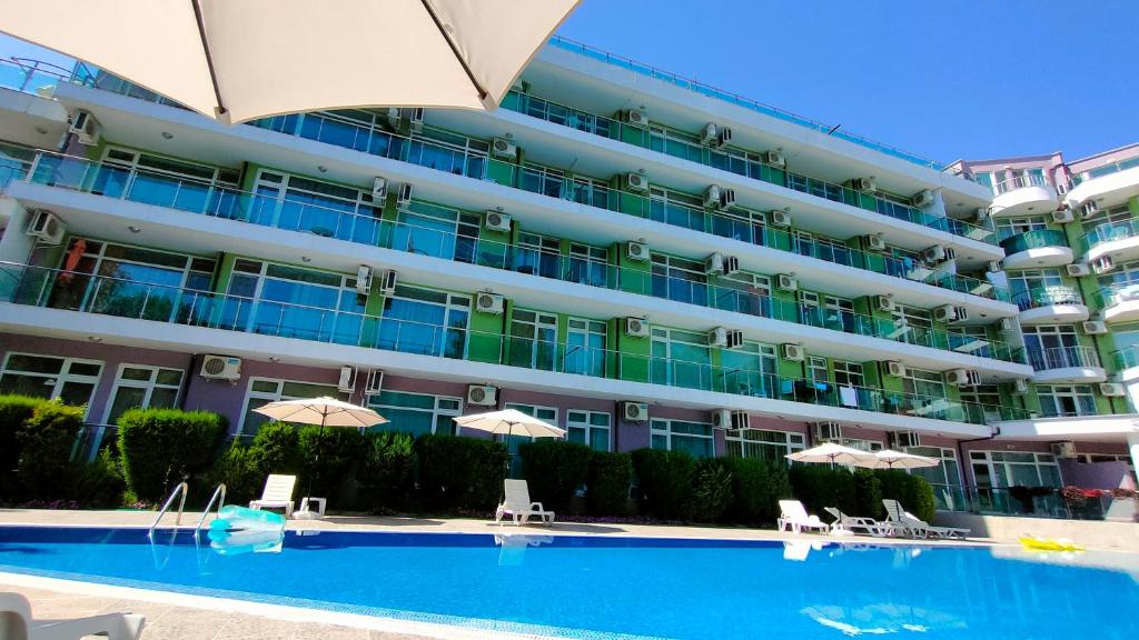 a large apartment building with a swimming pool and umbrellas at Sunny Beach Studio in Apartcomplex Solmarine in Sunny Beach