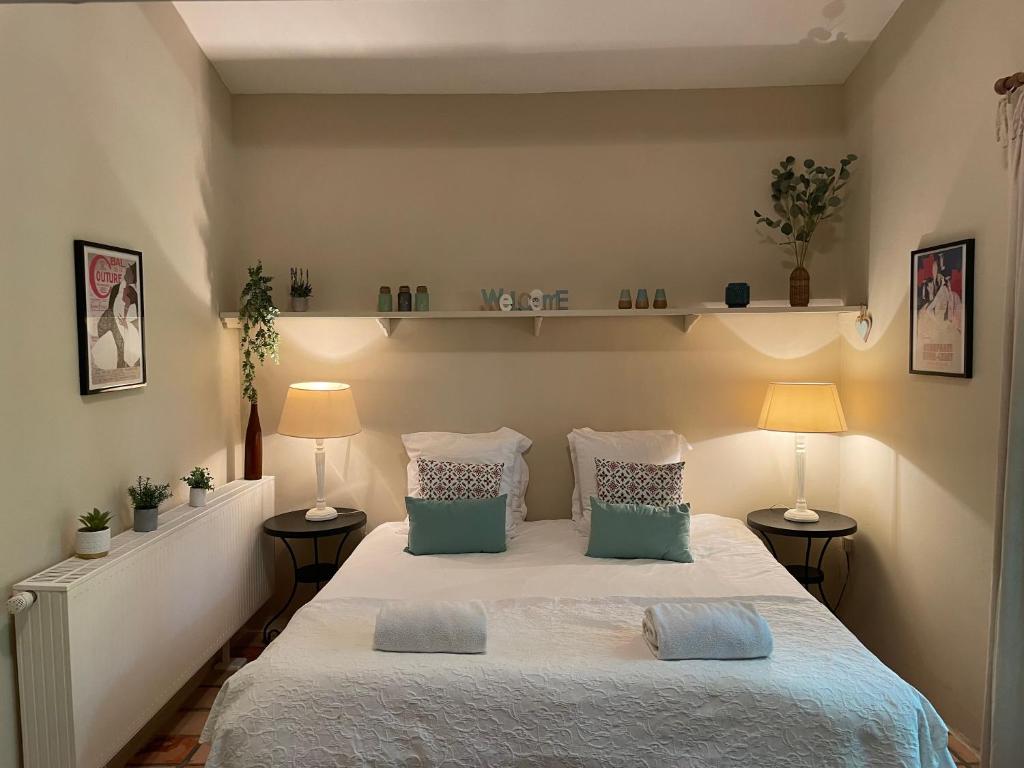 une chambre avec un lit avec des oreillers et deux lampes dans l'établissement The Garden Room, à Villamblard