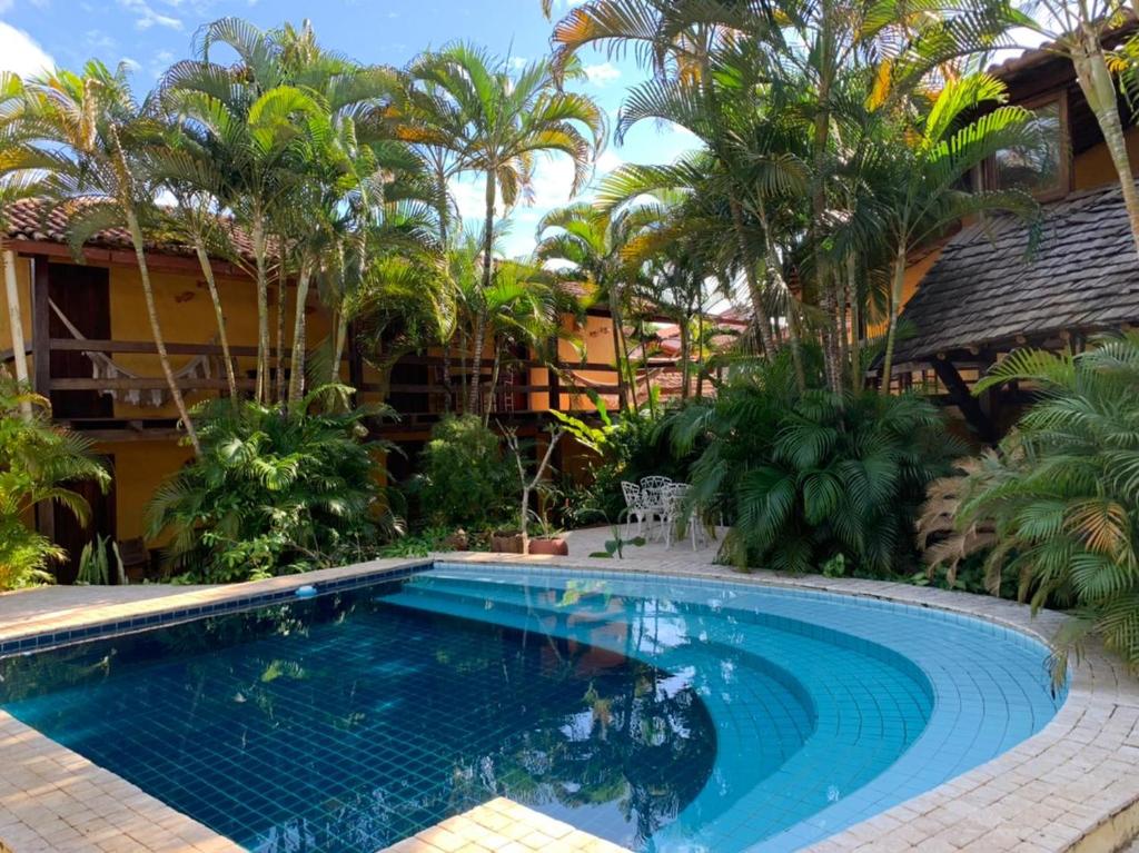 a swimming pool in front of a house with palm trees at Pousada Refugium in Itacaré