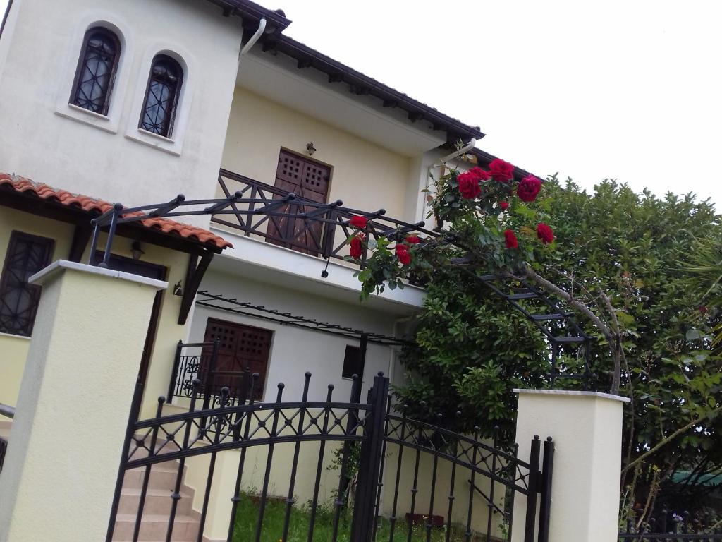 a white house with a fence and red roses at Marianthi's House in Metamorfosi