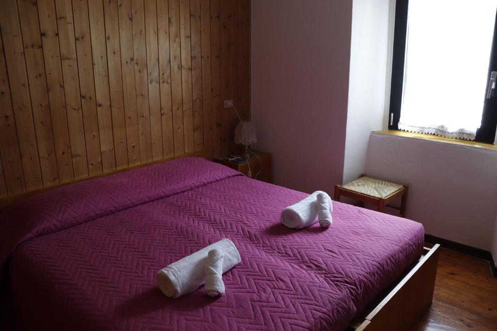 a bedroom with a purple bed with towels on it at B&B Amico in Comano Terme