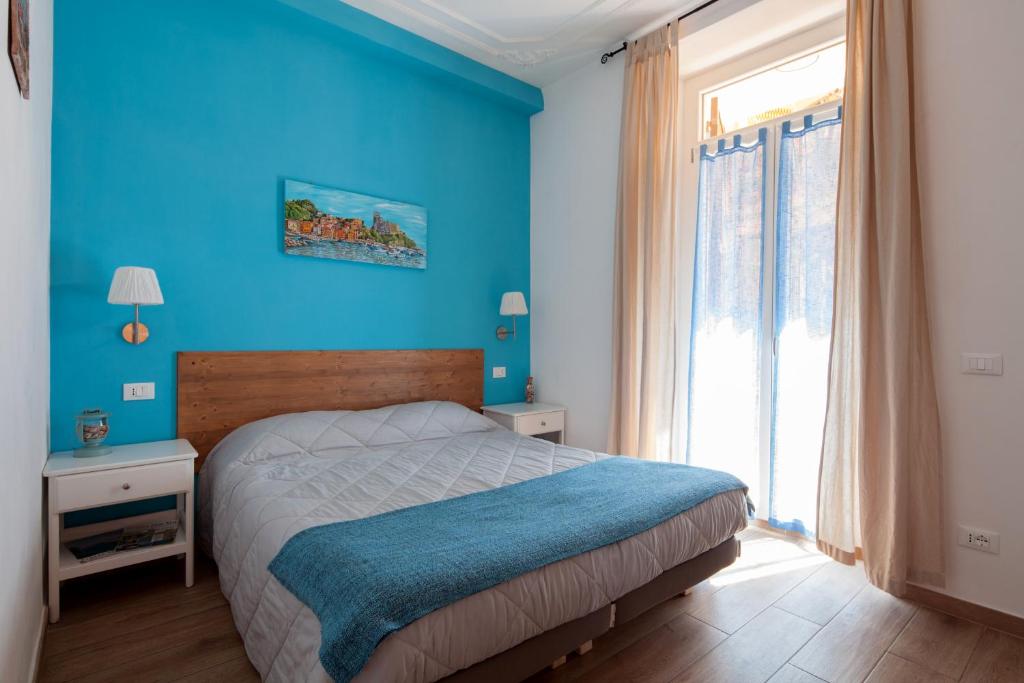 Dormitorio azul con cama y ventana grande en Sciuscettùa Rooms, en La Spezia