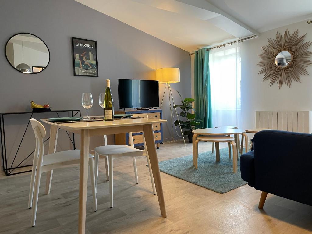 sala de estar con mesa, sillas y TV en Chez Emile La Chabotine -T2 Neuf, calme, lumineux, en Niort