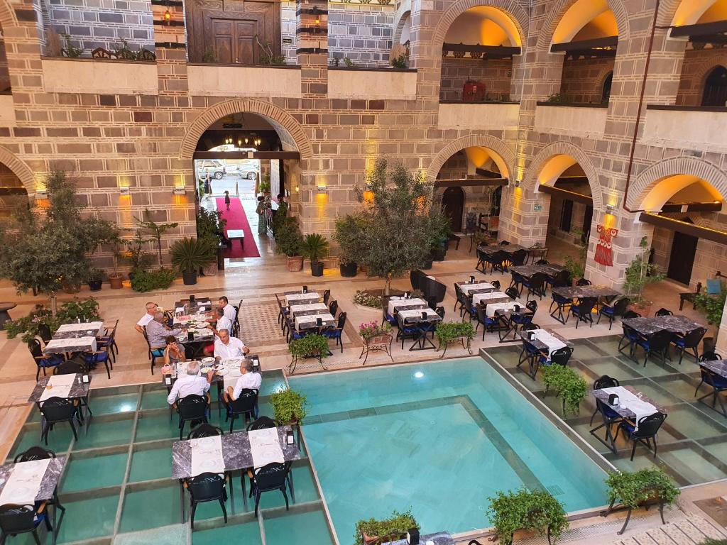 een overdekt restaurant met een zwembad in een gebouw bij Cesme Kanuni Kervansaray Historical Hotel in Çeşme