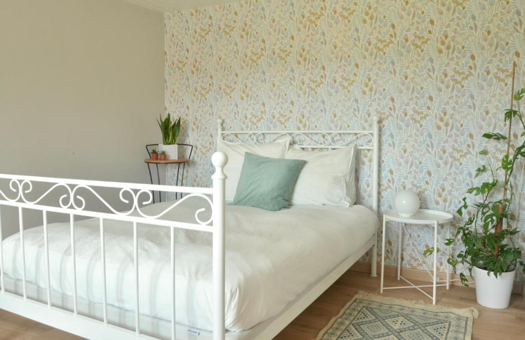 ein Schlafzimmer mit einem weißen Bett und einer Wand in der Unterkunft La Ferme aux Cinq Sens in Bussière-Boffy