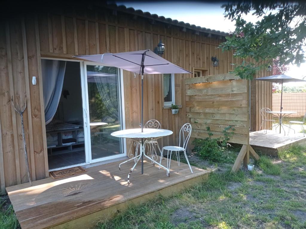 een patio met een tafel en een parasol op een terras bij les chambres du pont des chèvres in Commensacq