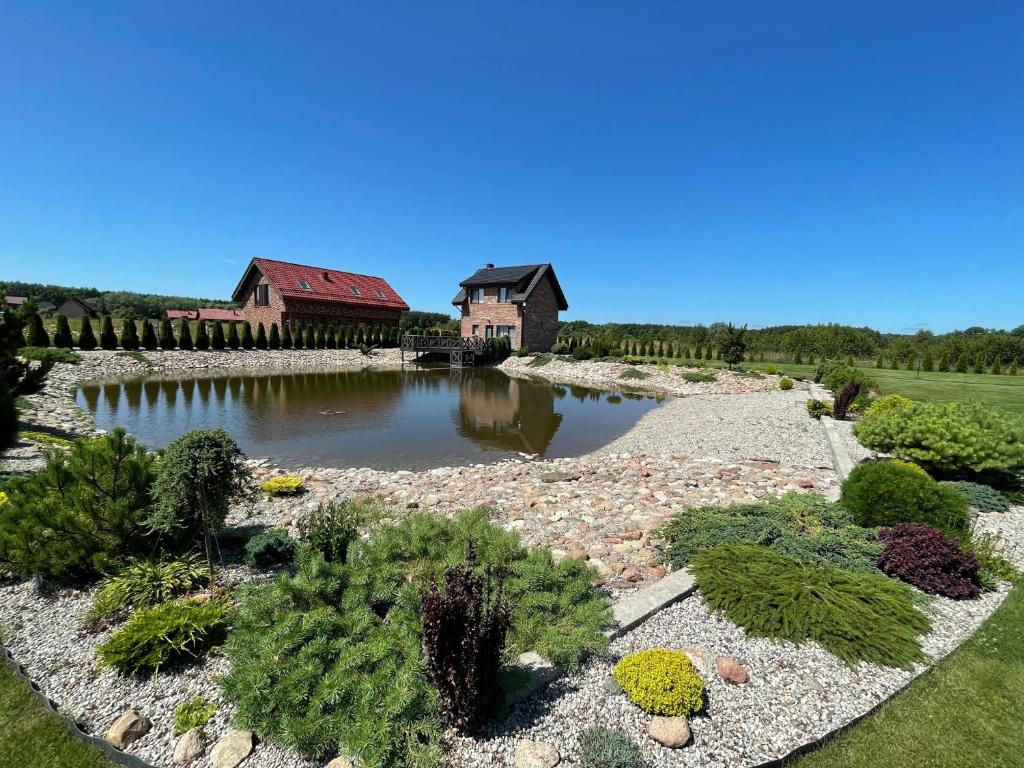 a garden with a house and a pond with plants at Karklės namelis in Karklė