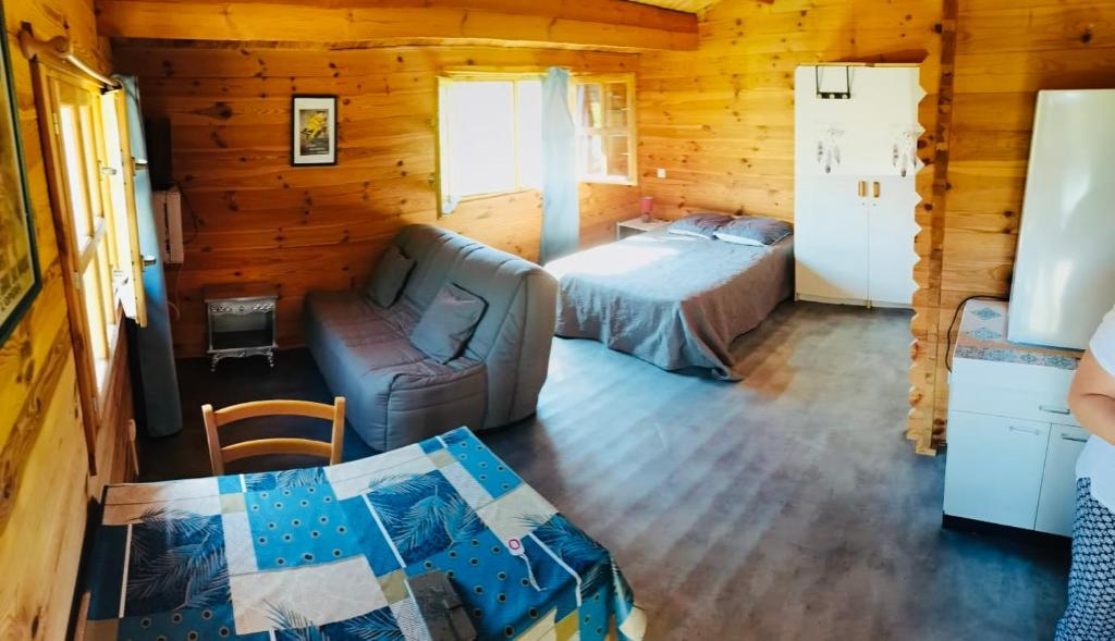 a bedroom with a bed and a couch in a log cabin at Studio Domaine du vieux chêne in Bergerac