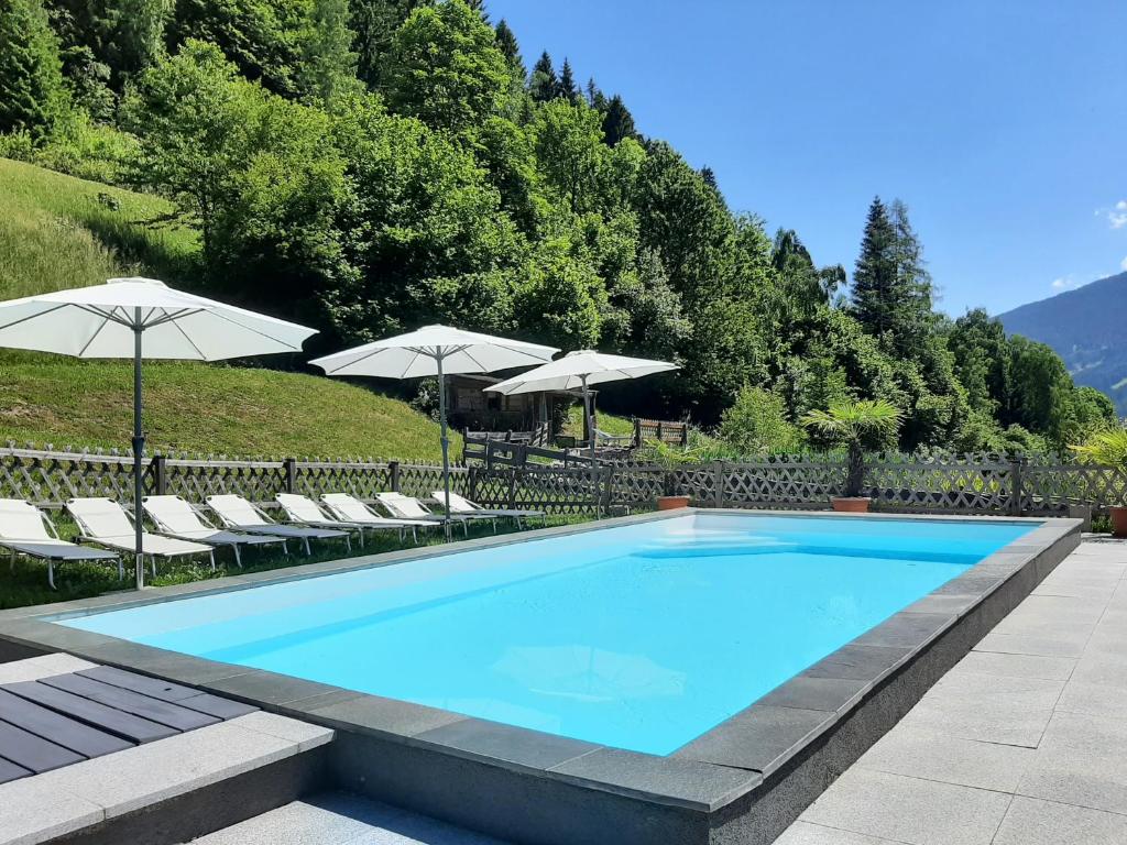 a large swimming pool with chairs and umbrellas at Landhof Kreuzsalgut in Wagrain