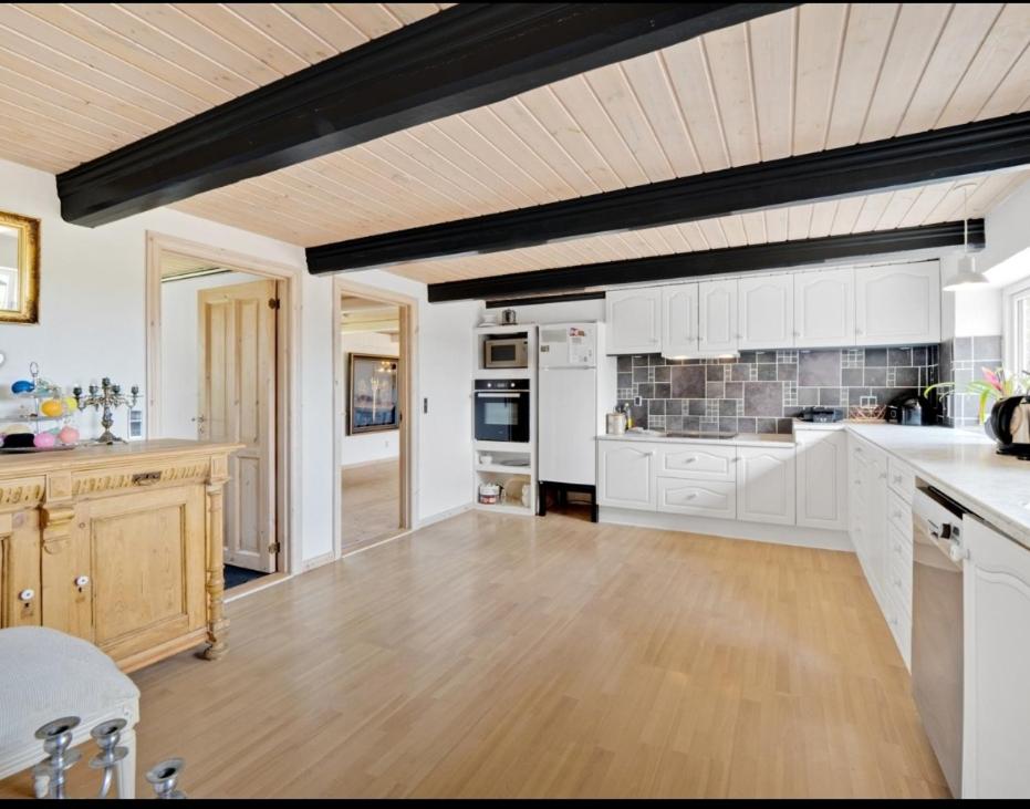 a large kitchen with white cabinets and a wooden floor at Villa Wunder in Spottrup