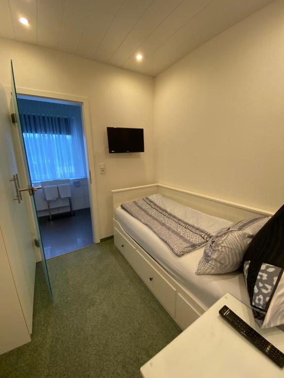 a small bedroom with a bed and a television at Hotel Pension Haus Talblick Edersee in Hemfurth-Edersee