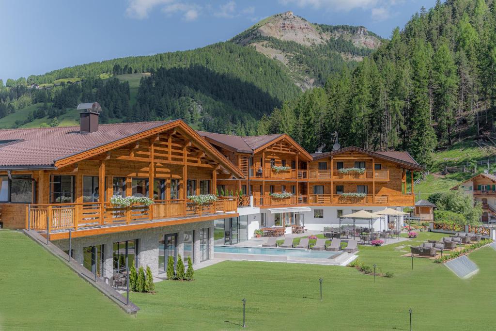 um grande edifício de madeira com uma montanha ao fundo em Hotel Rodella em Selva di Val Gardena