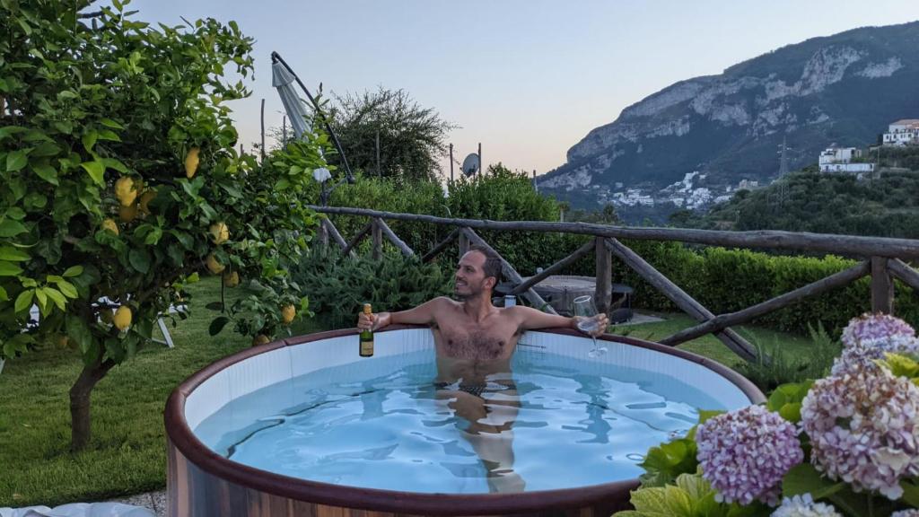 a man in a hot tub in a garden at Suite Lia - Private Room with garden and tub close to Villa Eva e Cimbrone, Ravello in Ravello