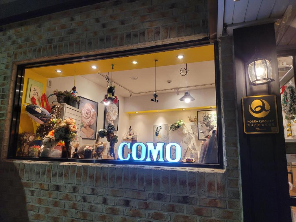 a store window with a sign that says como at Myeongdong Guesthouse Como in Seoul