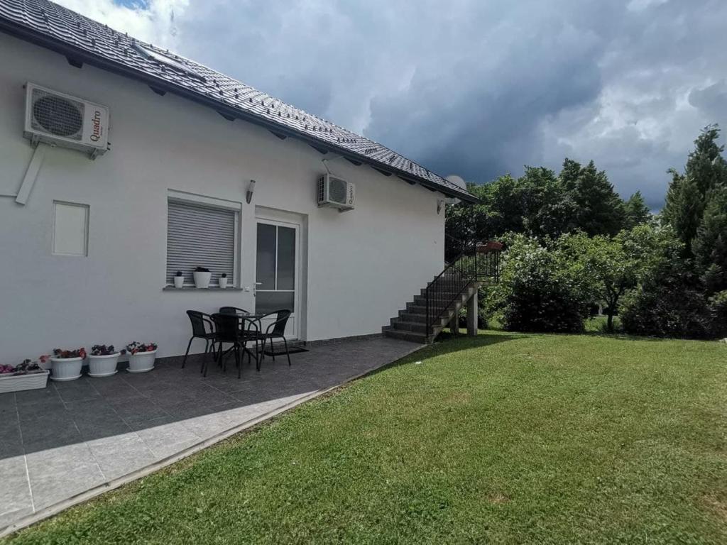 een wit huis met een tafel en stoelen in een tuin bij New apartment near Plitvice lakes in Smoljanac