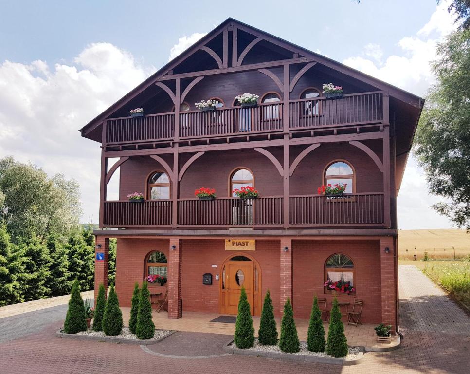 a large house with a balcony and plants at Gościniec Piast Hotel i Camping in Brzeźno