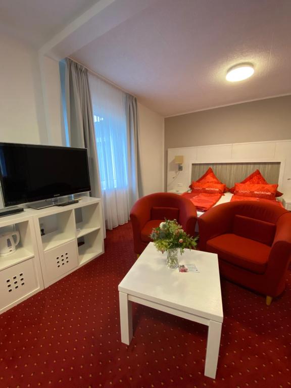 a living room with red furniture and a flat screen tv at Hotel Pension Haus Talblick Edersee in Hemfurth-Edersee