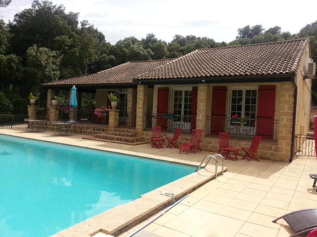 una casa con piscina y sillas rojas en La Combe Joseph, en Remoulins