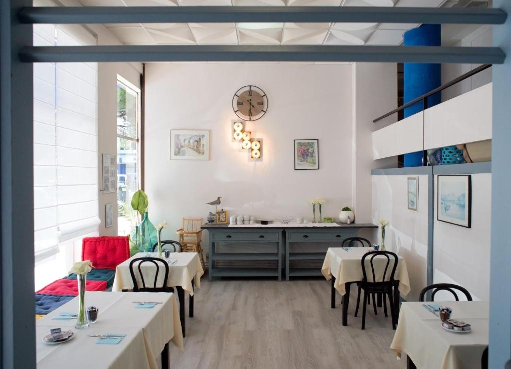 un comedor con mesas y sillas blancas en Hôtel Aunis-Saintonge, en Royan