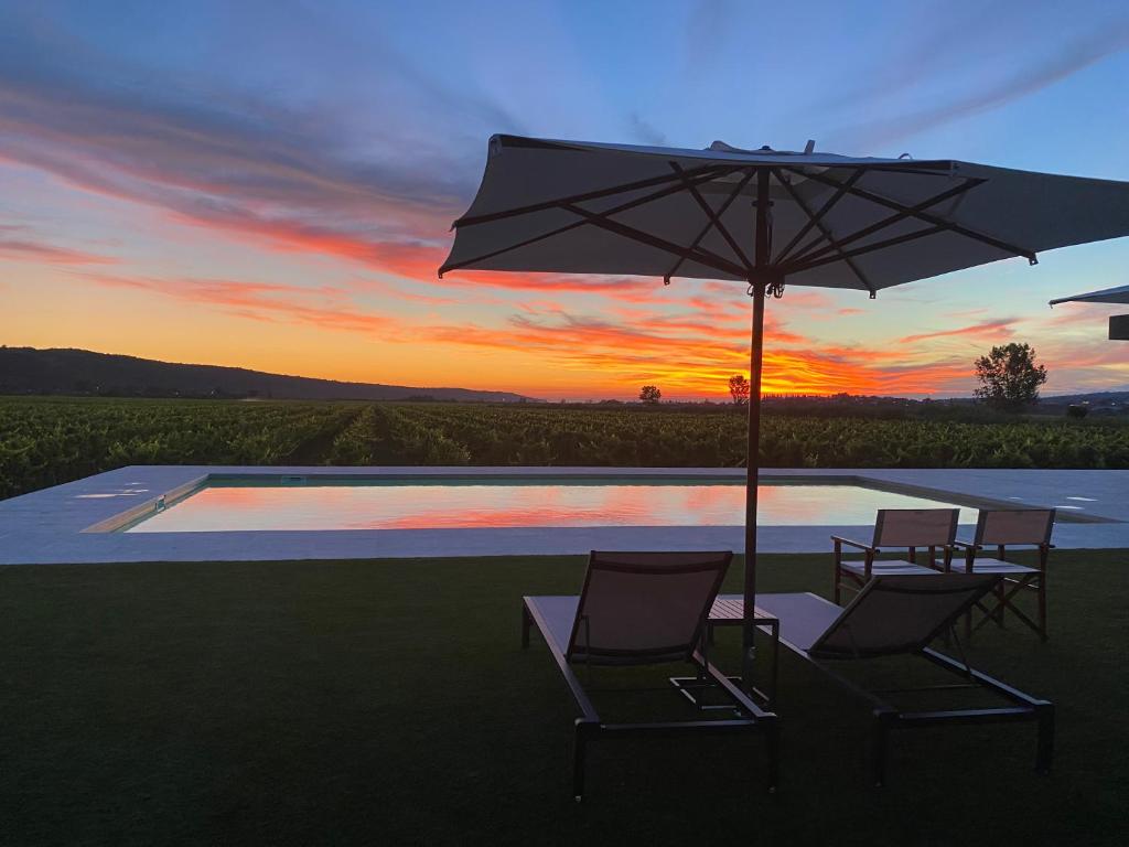 two chairs and a table with an umbrella next to a pool at Casa Mulino - where the vineyards meet the sea in Sečovlje