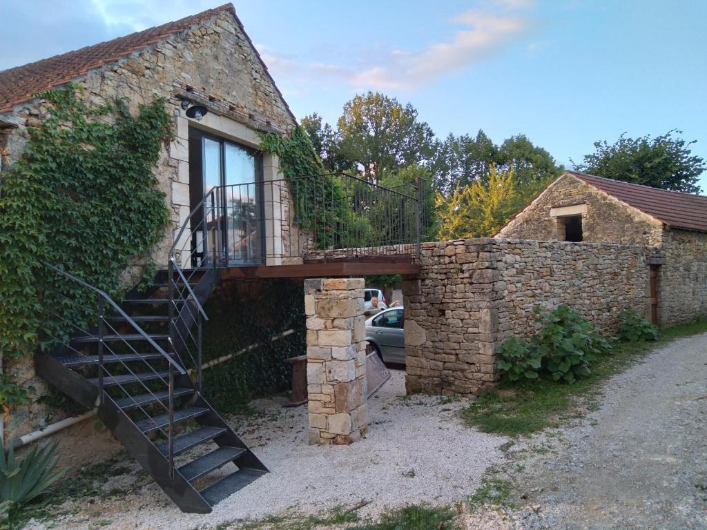 a stone house with a staircase next to a building at Le Nid d'été in Montcléra