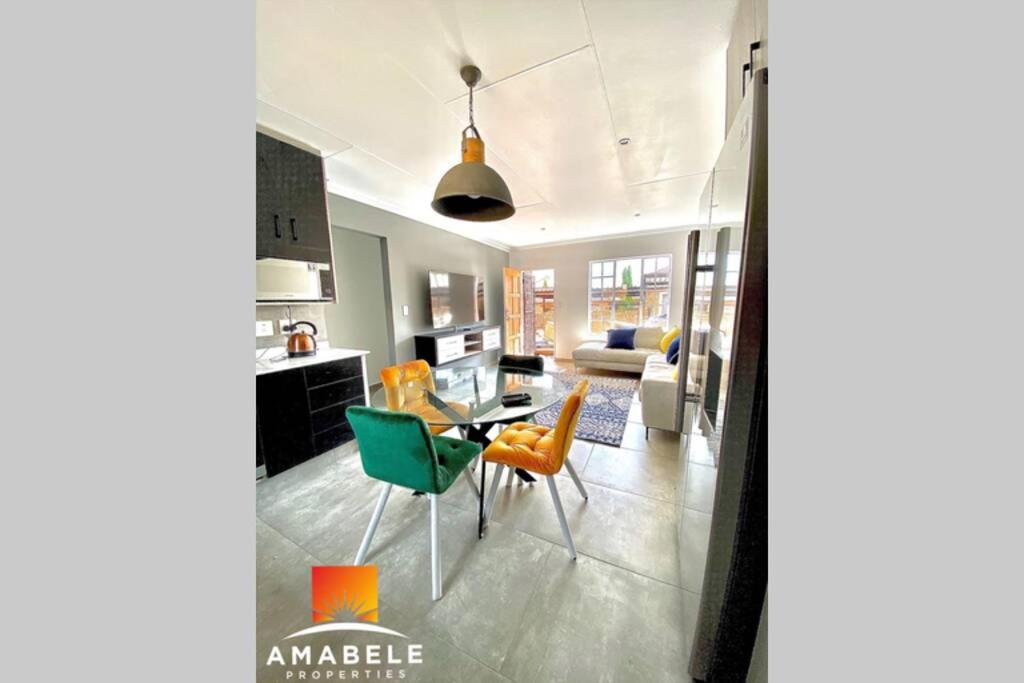 eine Küche und ein Wohnzimmer mit einem Tisch und Stühlen in der Unterkunft Castle45 in Roodepoort