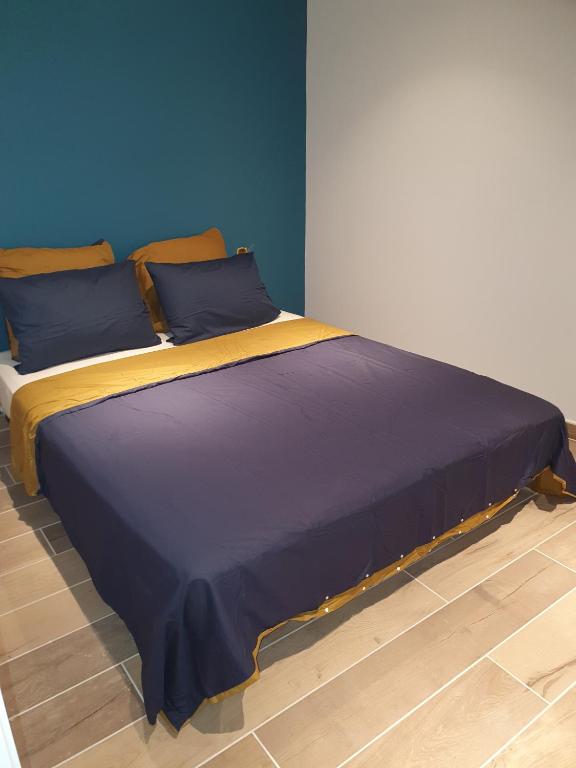 een groot bed met een blauwe en gele deken bij Les Suites du Relais in Saint-Martin-dʼAblois