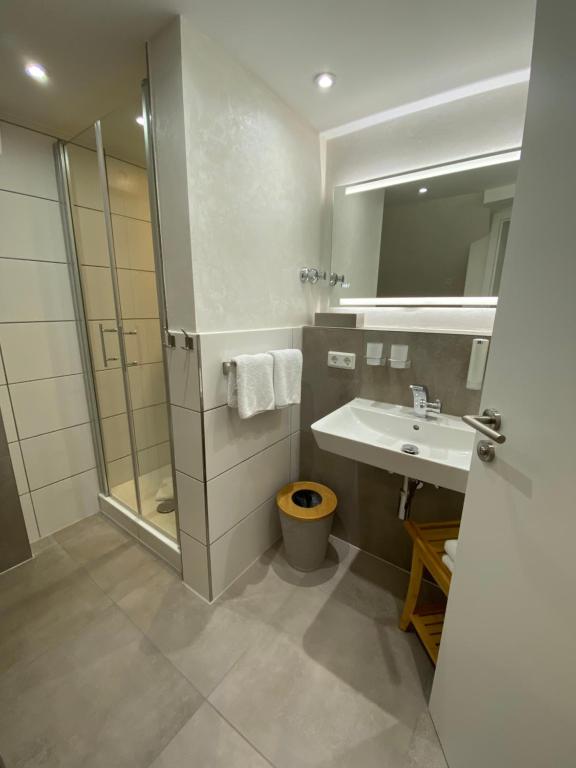 a bathroom with a sink and a shower and a mirror at Hotel Pension Haus Talblick Edersee in Hemfurth-Edersee