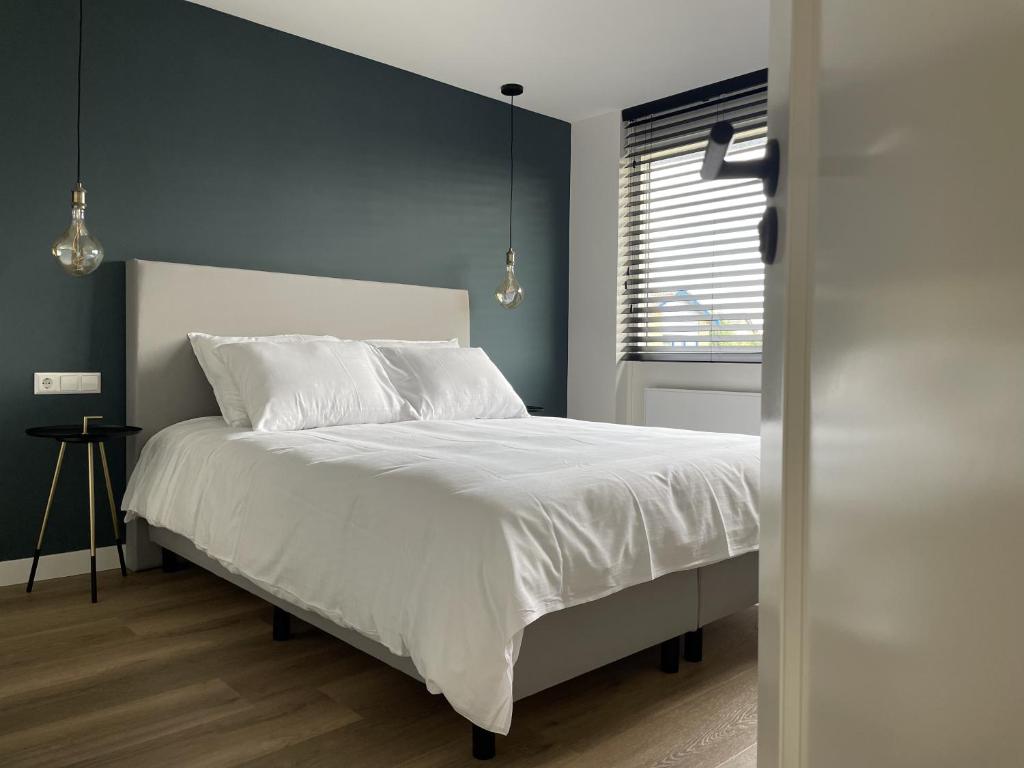 Schlafzimmer mit einem Bett mit weißer Bettwäsche und einem Fenster in der Unterkunft N9 Texel in De Koog