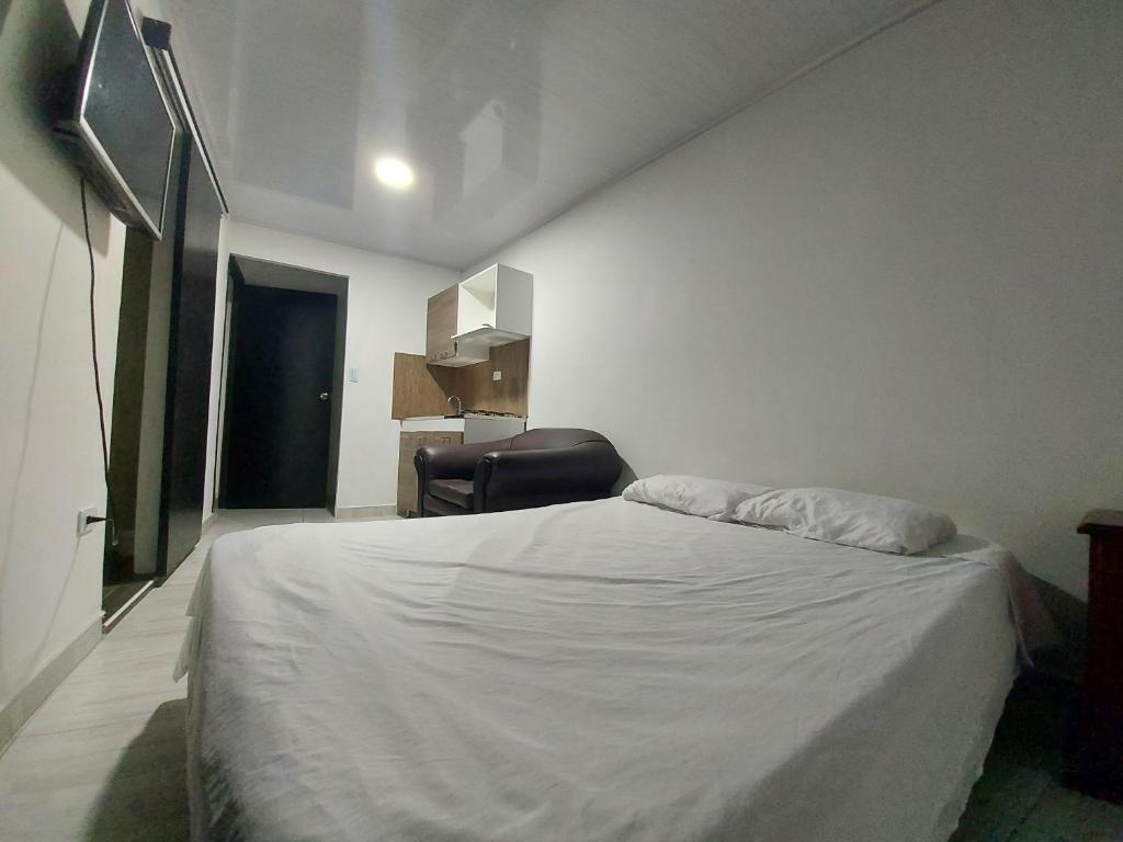 Un dormitorio con una cama blanca y una silla. en Apartaestudio6 sector Cable Estadio, en Manizales
