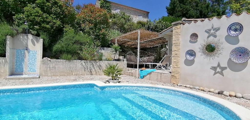 een zwembad in een tuin naast een muur bij La Cayrade in Uzer