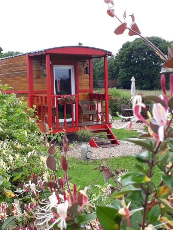 een kleine rode hut in een tuin met bloemen bij laroulottedubec in Malleville-sur-le-Bec