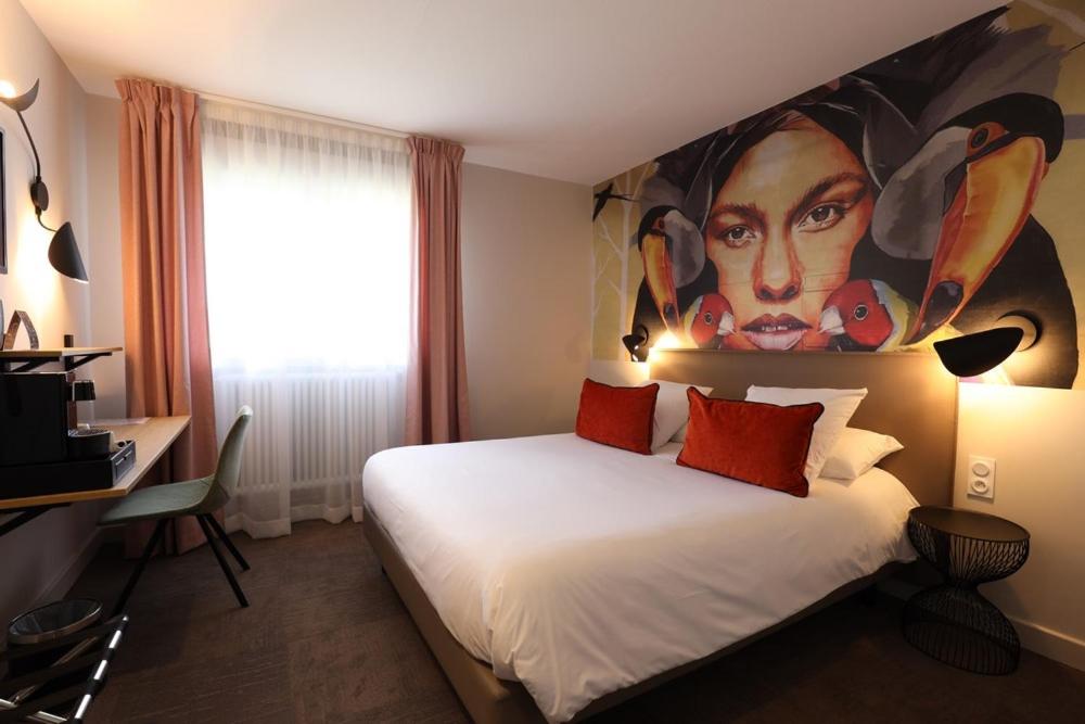 a hotel room with a bed with a painting on the wall at Hôtel la Capelle Millau in Millau