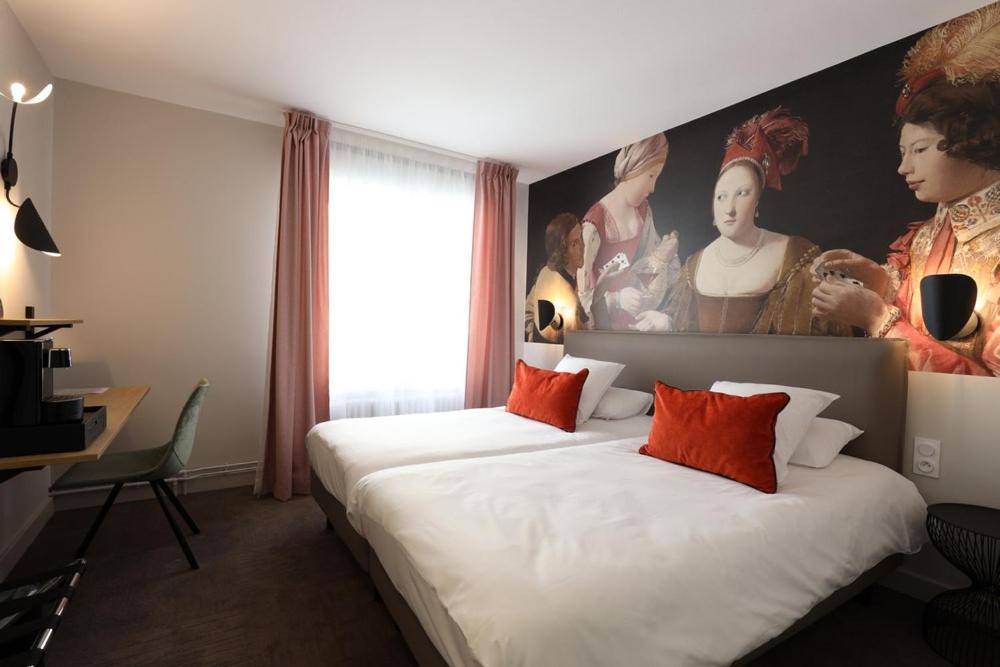 a bedroom with a large bed with a painting on the wall at Hôtel la Capelle Millau in Millau