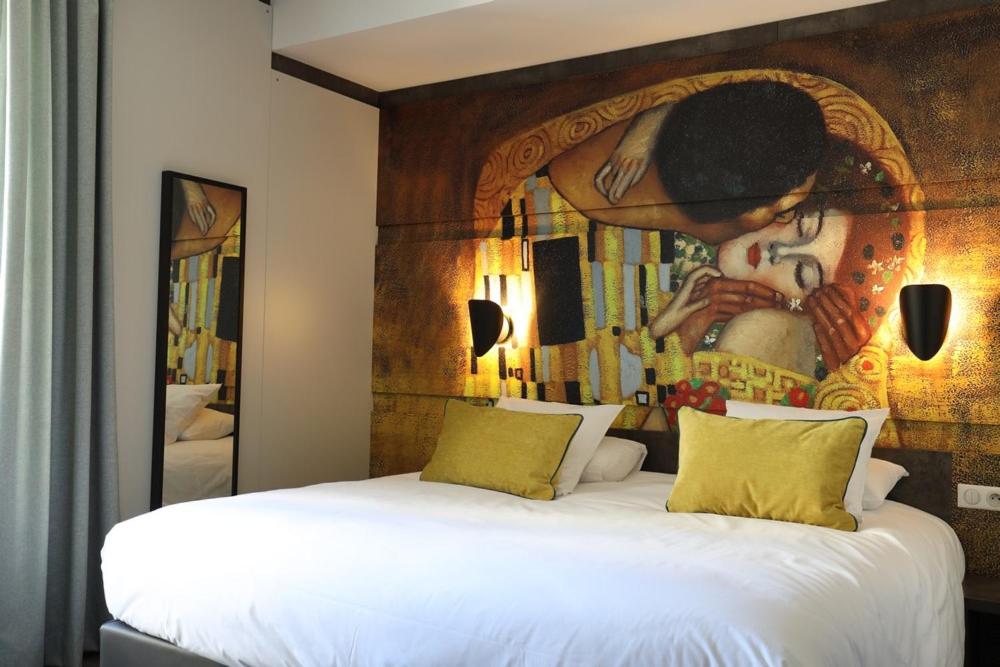 a bedroom with a painting on the wall next to a bed at Hôtel la Capelle Millau in Millau