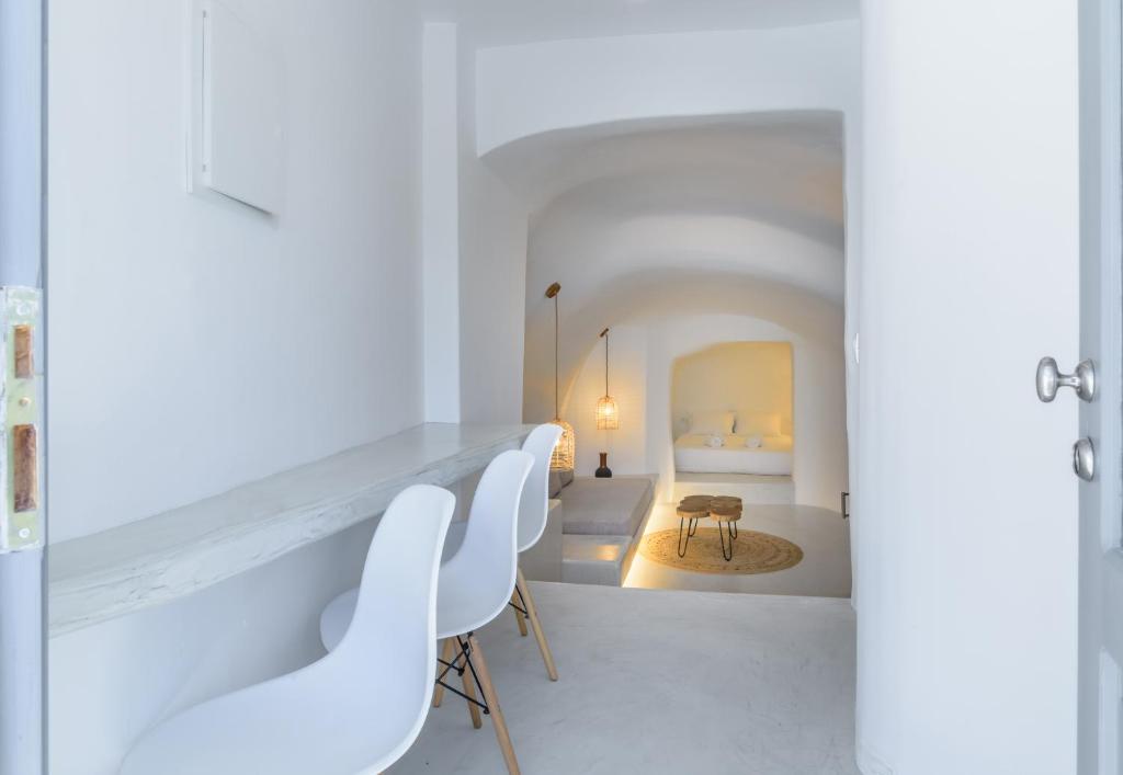 a white room with white chairs and a bedroom at Anila Suites in Fira