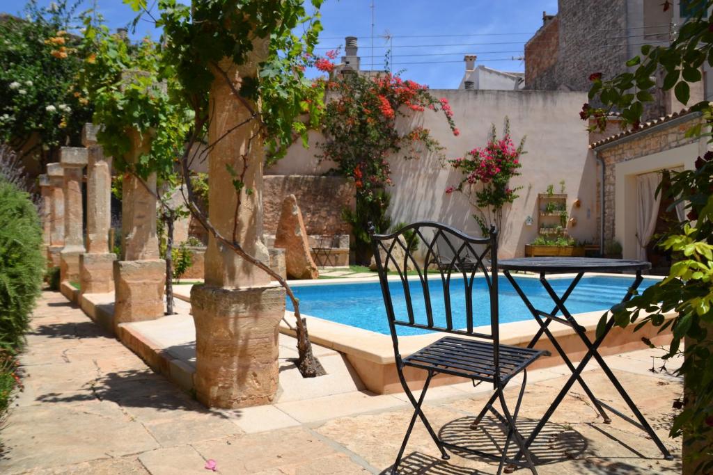 Una mesa y sillas junto a una piscina. en CAL SENYOR DAMIÀ, en Santanyí