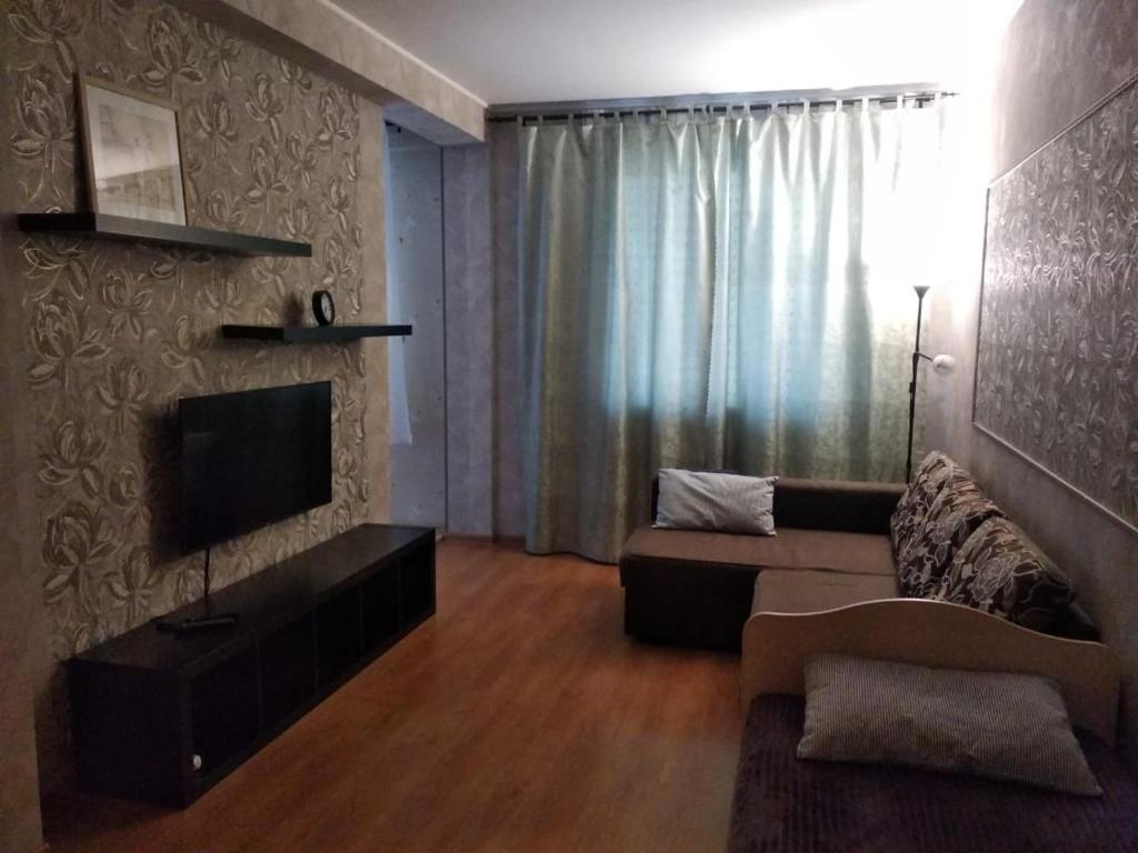 uma sala de estar com um sofá e uma televisão de ecrã plano em 1к. Апартаменты НСК , на Блюхера 71б. em Novosibirsk