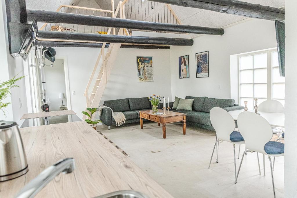 a living room with a green couch and white chairs at Ferielejlighed Holmevej in Næstved