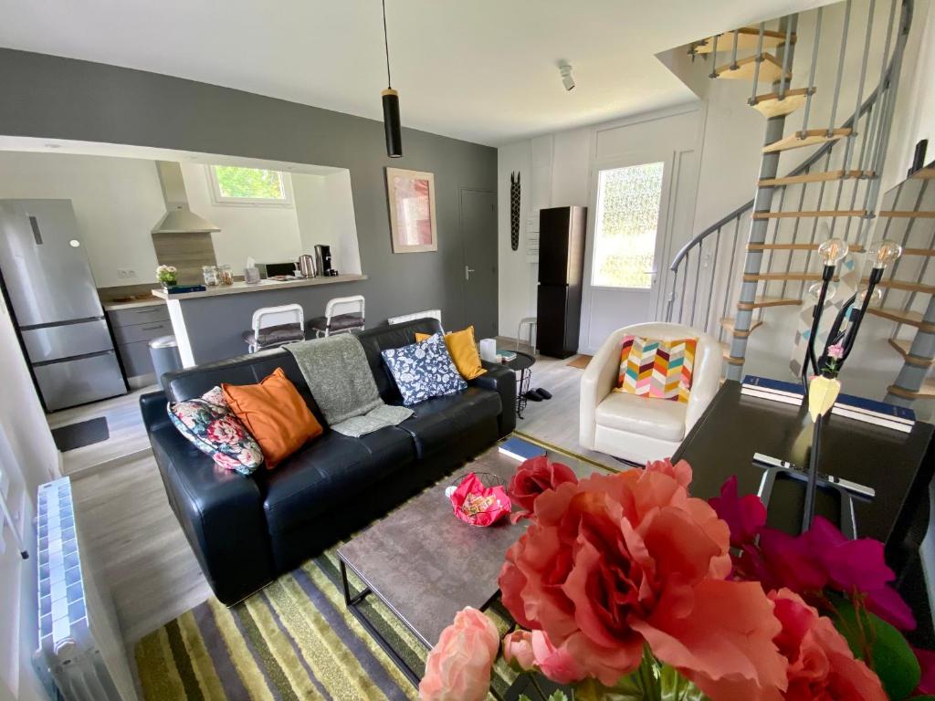 a living room with a black couch and a kitchen at Jiwe in Chilleurs-aux-Bois