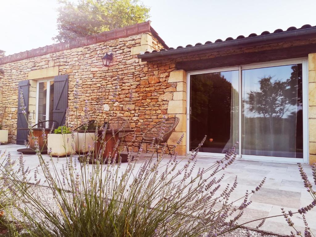 a stone house with glass doors and a patio at Ô Rêve de Gabriel in Saint-Amand-de-Coly