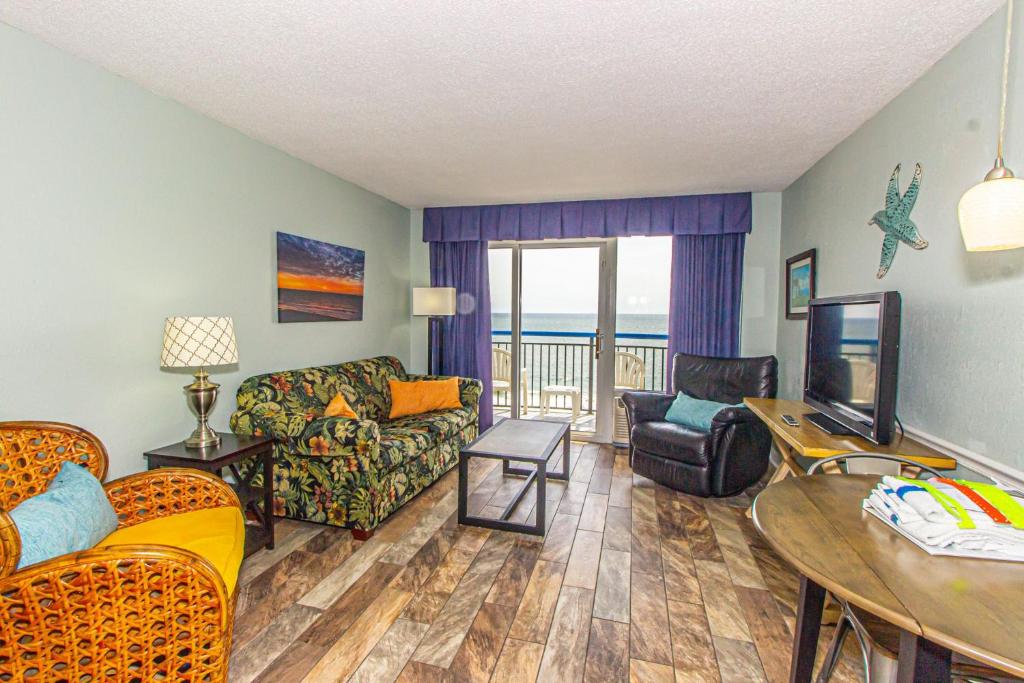 een woonkamer met een bank, een tafel en een televisie bij Boardwalk 1030 in Myrtle Beach