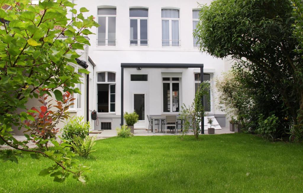 une maison blanche avec une pelouse devant elle dans l'établissement Le Jardin de Ligny, à Saint-Omer