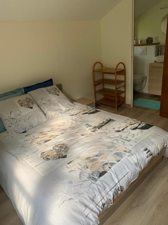 ein Schlafzimmer mit einem Bett mit weißer Bettwäsche und einem Stuhl in der Unterkunft Le paradis des oiseaux in Saint-Gildas