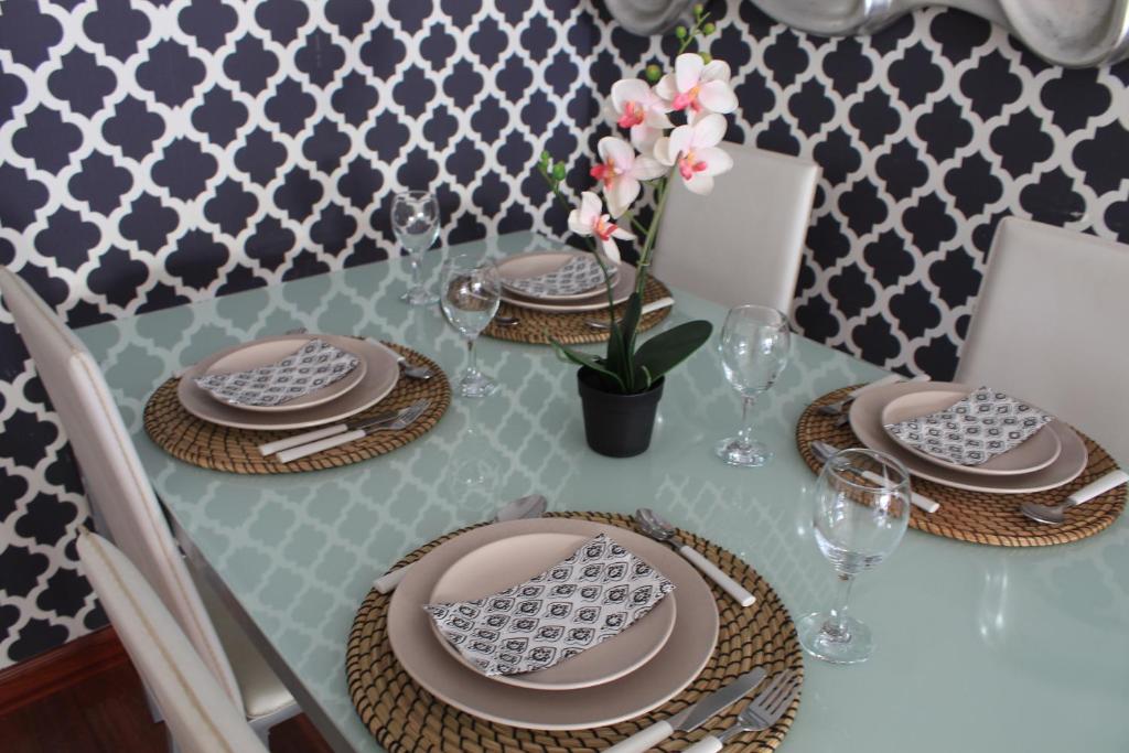 a table with plates and glasses and a vase with flowers at ACOGEDOR APARMENTO JUNTO AL CENTRO in Huelva