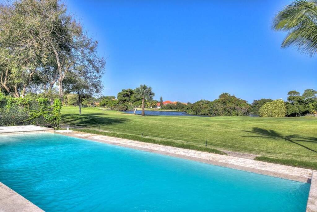 niebieski basen w ogrodzie z zielonym polem w obiekcie Luxury, golf and comfort in the Caribbean w Punta Cana