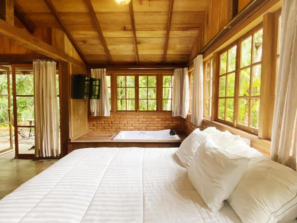 1 cama blanca grande en una habitación con ventanas en Kanawha Hotel, en Nova Friburgo