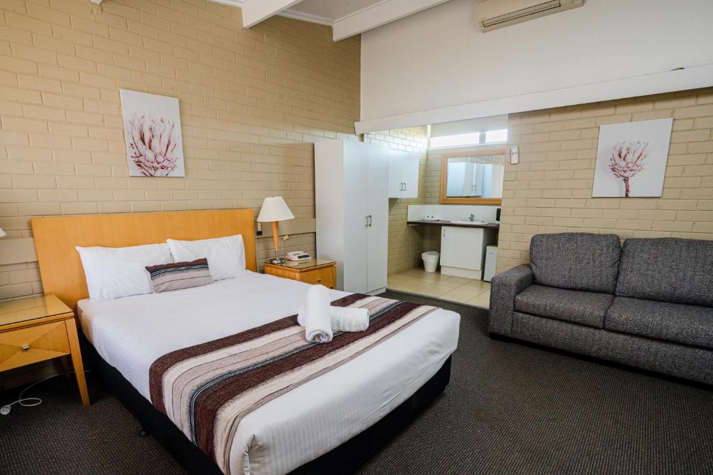 a bedroom with a bed and a couch and a chair at Parkview Motor Inn in Parkes