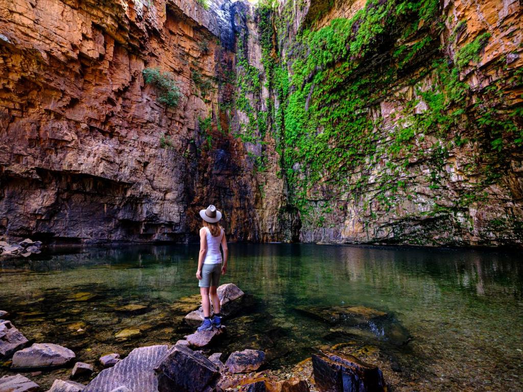 a woman standing on a rock in a river at Emma Gorge Resort at El Questro in Kununurra